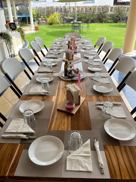Mesa larga montada para un festejo en la terraza