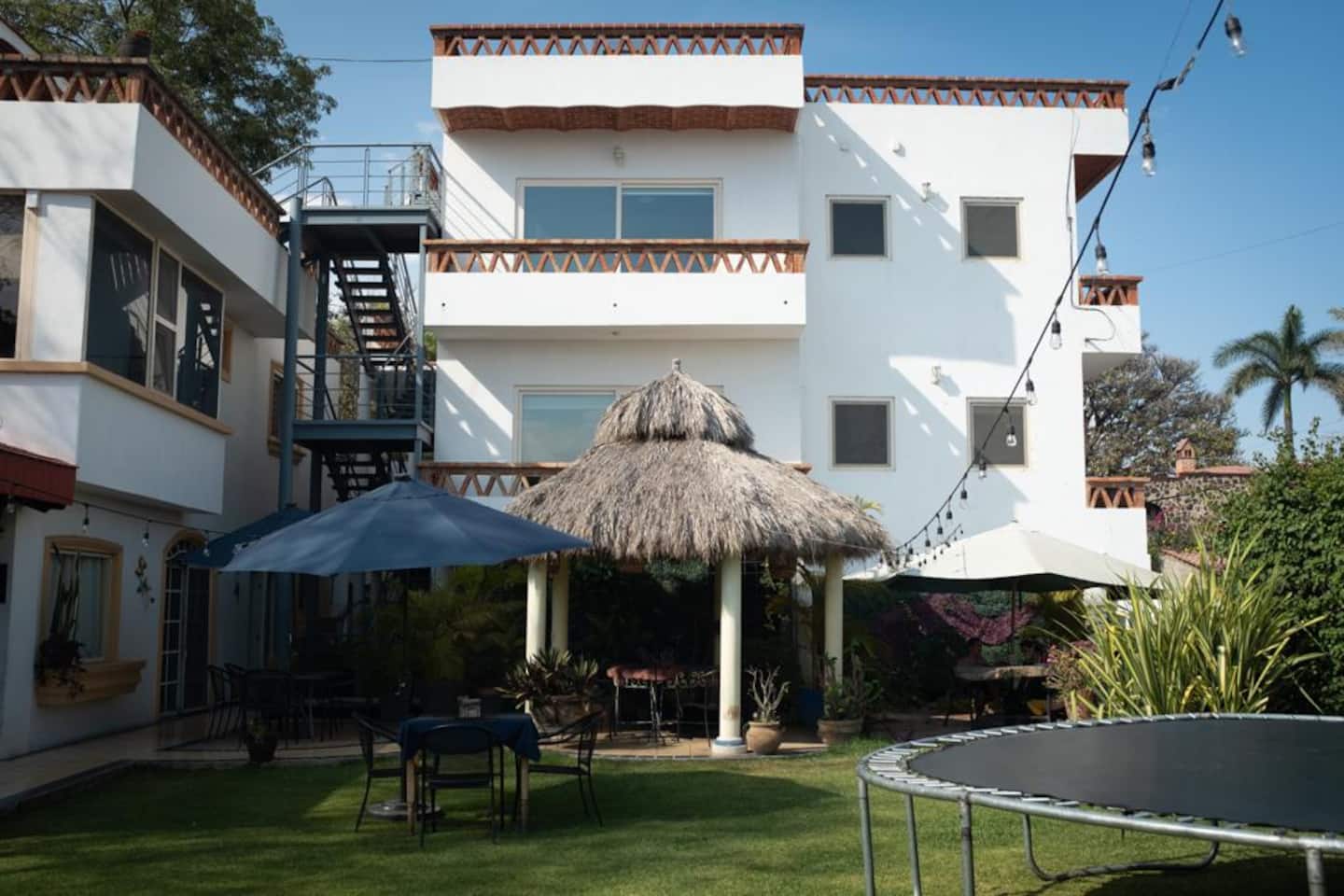 Fachada blanca de Casa Barragán con la palapa y el jardín